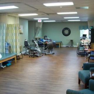 A spacious physical therapy clinic with various exercise equipment and treatment areas.