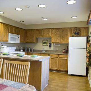 A modern kitchen with wooden cabinets, a refrigerator, and a microwave, complete with a dining table.