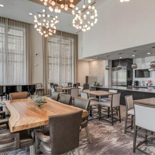 A modern dining area with a large wooden table and stylish chandeliers.