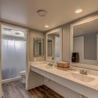 A modern bathroom featuring double vanities, large mirrors, and a stylish shower area.