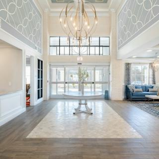 A spacious and elegantly designed lobby area with a modern chandelier and large windows.