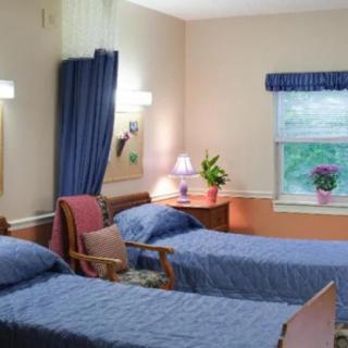 A hospital room with two beds, a chair, and a desk.