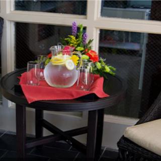 A small round table decorated with a vase of colorful flowers and a pitcher of lemonade, accompanied by glasses and set on a red napkin.