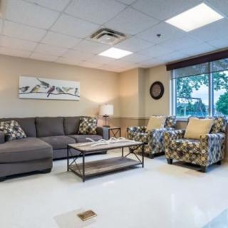 A cozy living room with a gray sofa, patterned armchairs, and a coffee table facing a large window.