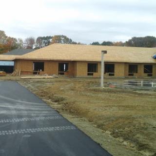A new building under construction, featuring a partially finished roof and surrounding landscaping.