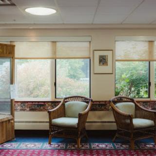 A cozy waiting area with wicker chairs and large windows allowing natural light.