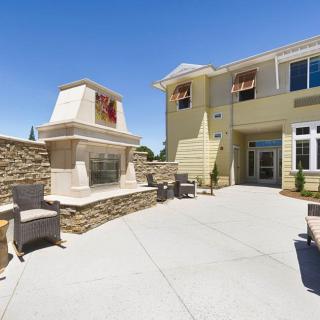 A sunny outdoor patio with a fireplace and comfortable seating.