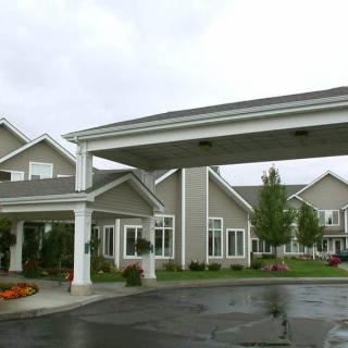 A modern building with a covered driveway entrance and landscaped surroundings on an overcast day.