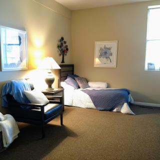 A cozy bedroom featuring a comfortable sofa, a stylish lamp, and framed artwork.