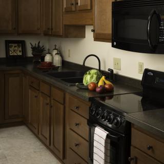 A cozy kitchen with wooden cabinets, a black countertop, and various appliances.