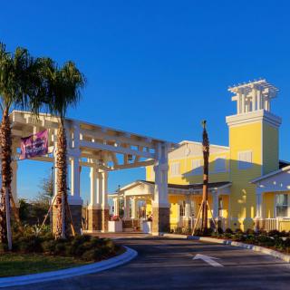 A sunny view of a resort entrance with palm trees and bright yellow architecture.