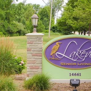 A landscaped area with a decorative sign and lamp post amid greenery.