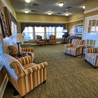 A cozy living room with striped chairs and ample natural light from large windows.
