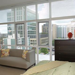 A modern apartment with large windows offering a cityscape view, featuring contemporary furniture and abundant natural light.