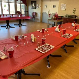 A long table set for a party with red tablecloths and decorations.