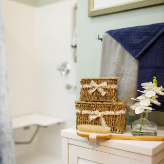 A neatly organized bathroom with decorative baskets, folded towels, and a small vase of flowers.
