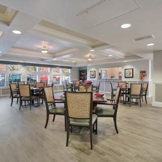 A modern dining area with neatly arranged tables and chairs, featuring tasteful decor and ambient lighting.