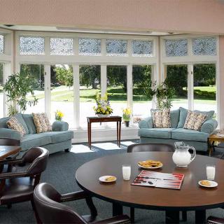 A cozy living room with large windows, two sofas, and a round table set for tea.