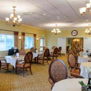 A well-lit dining room with elegant furniture and chandeliers.