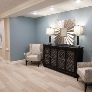A modern living room setup with stylish furniture, featuring a decorative mirror and lamps.