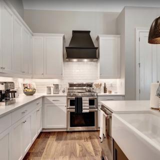 A modern kitchen with white cabinets and stainless steel appliances.