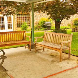 Wooden benches on a shaded patio overlook a lush garden.