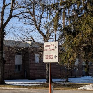 A directional sign in front of a building, surrounded by trees and snow.