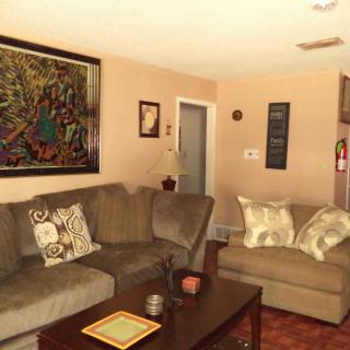 A cozy living room with a comfortable couch, decorative pillows, and a coffee table adorned with art pieces and a lamp.