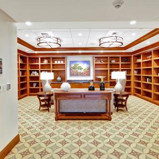 A well-designed office space featuring wooden bookshelves, a desk, and elegant lighting.