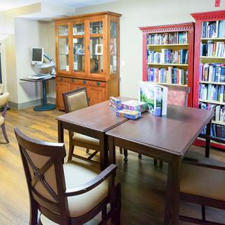 A cozy reading room with bookshelves filled with books, a table, and chairs.
