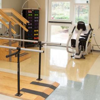 A physical therapy room equipped with parallel bars and exercise machinery for rehabilitation.
