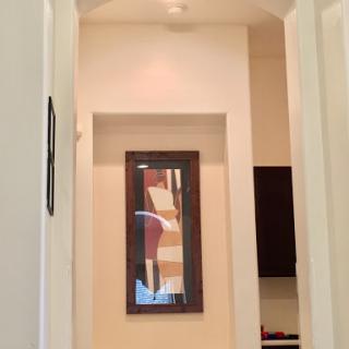 A view of a well-lit hallway featuring an abstract framed artwork.