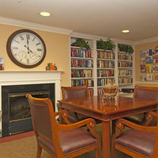 A cozy reading room with a large clock, bookshelves, and comfortable seating.