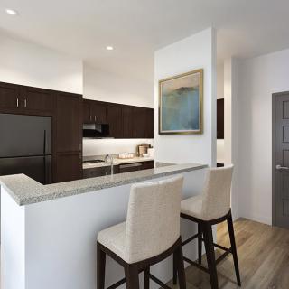 A modern kitchen featuring a sleek countertop with bar stools and contemporary appliances.