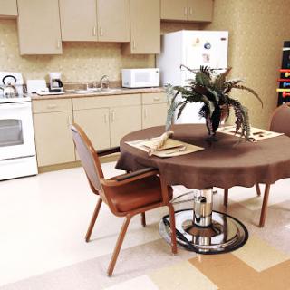 A cozy kitchen area featuring a round table, comfortable chairs, and modern appliances.