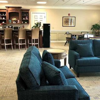 A cozy living space featuring blue couches, a bar area, and beige carpeting.