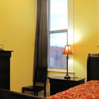 A cozy bedroom with a lamp on the nightstand by the window.