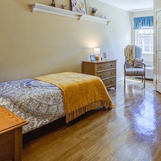 A cozy bedroom with wooden flooring and neatly arranged furniture.