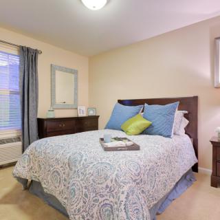 A cozy bedroom with a neatly made bed, pillows, and neutral decor.
