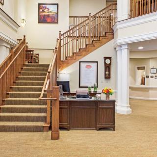 A welcoming lobby area featuring a staircase and reception desk with classic interior design elements.