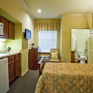 A cozy hotel room featuring a kitchenette, comfortable seating, and an adjoining bathroom.