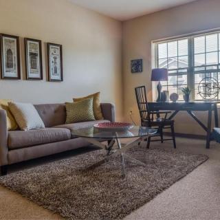 A cozy living room with a sofa, coffee table, and desk near a window.