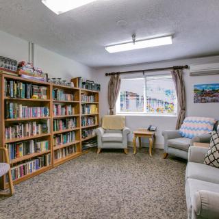 A cozy library room with bookshelves filled with books and comfortable armchairs by the window.
