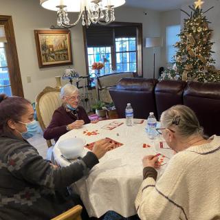 Elderly individuals enjoying a communal activity at a table near a decorated Christmas tree.