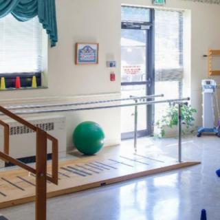 A rehabilitation room equipped with parallel bars and exercise equipment for physical therapy sessions.