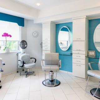 A modern and stylish hair salon interior with bright lighting, comfortable chairs, and large mirrors.