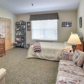 A cozy bedroom with a single bed, patterned sofa, and a well-lit window.
