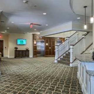 A spacious lobby featuring a carpeted floor, staircase, and modern lighting.