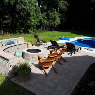 A beautiful outdoor space featuring a swimming pool, a cozy fire pit area, and comfortable seating, perfect for relaxation and entertaining.