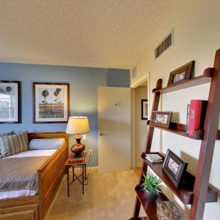 A cozy bedroom with a decorative shelf and framed artwork on blue and cream walls.